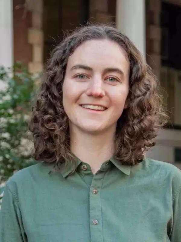 mixed background, woman smiling with brown wavy hair, sage green collared shirt